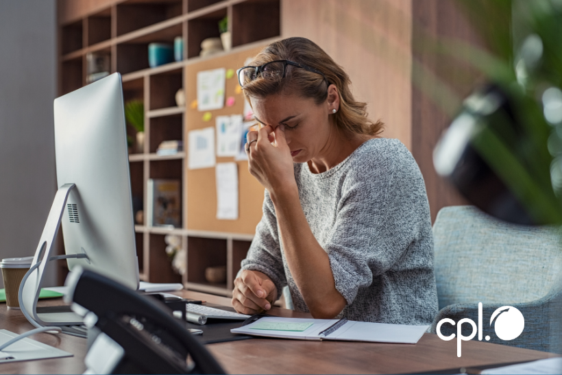 Woman sitting at her work desk looking unhappy.