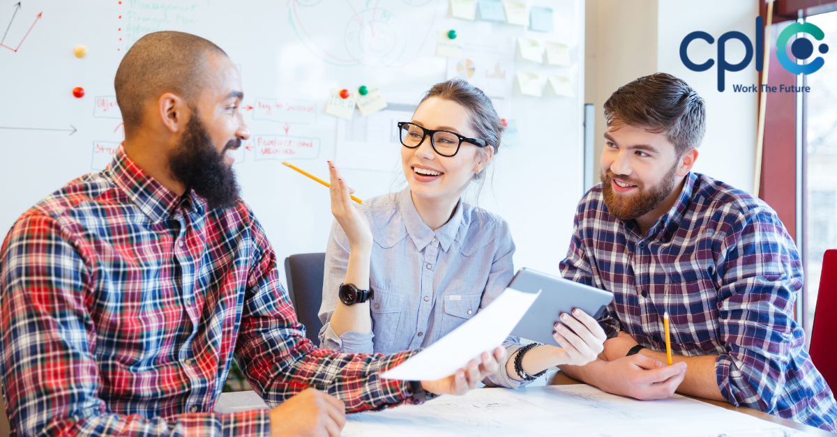 Co-workers smile whilst working together at a desk