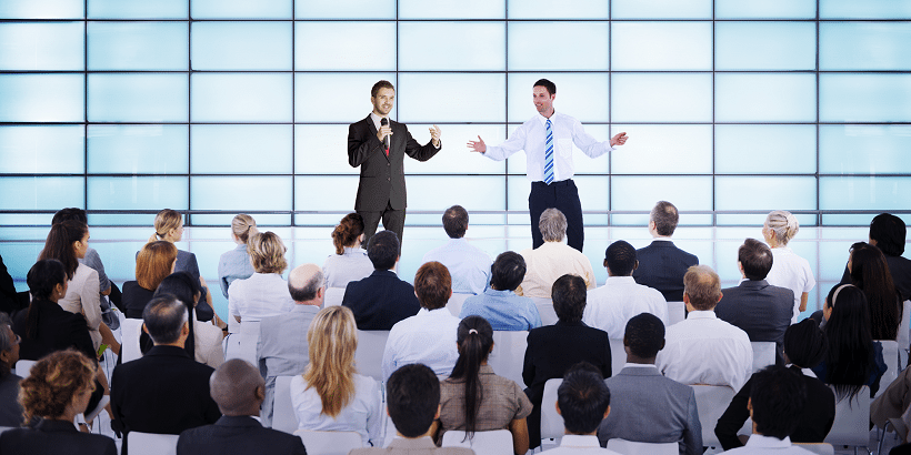 Two men giving a presentation in front of a workplace. 